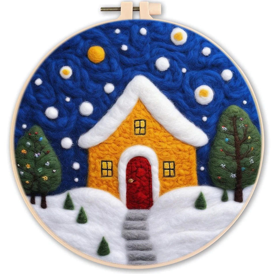 Needle felted night scene with a snow covered house, decorated trees, and big white and orange balls in the sky.