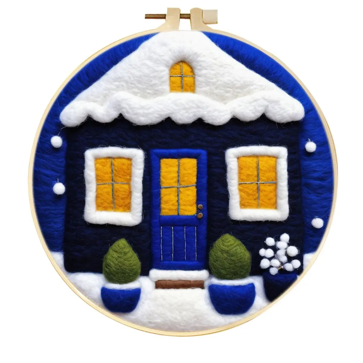 Needle felted winter house with snow on the roof and ground against a dark blue sky
