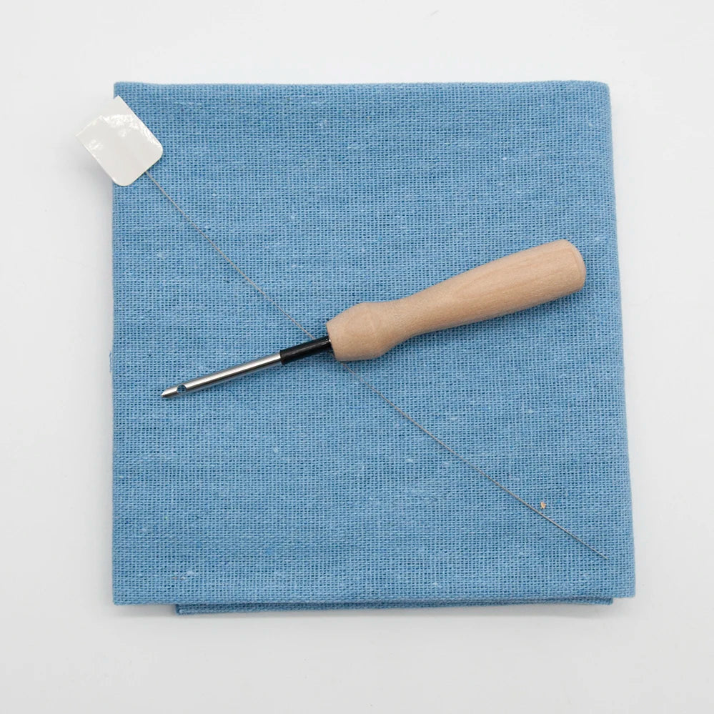 Blue fabric with a wooden-handled tool on a white background