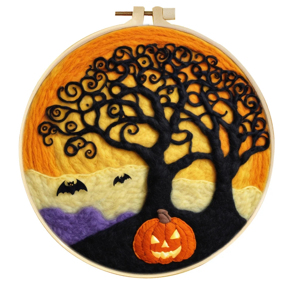 A circular needle felted design in a wooden hoop, featuring a black stylized tree against a yellow and orange sky, with purple hills, two black bats, and an orange jack-o'-lantern at the bottom.