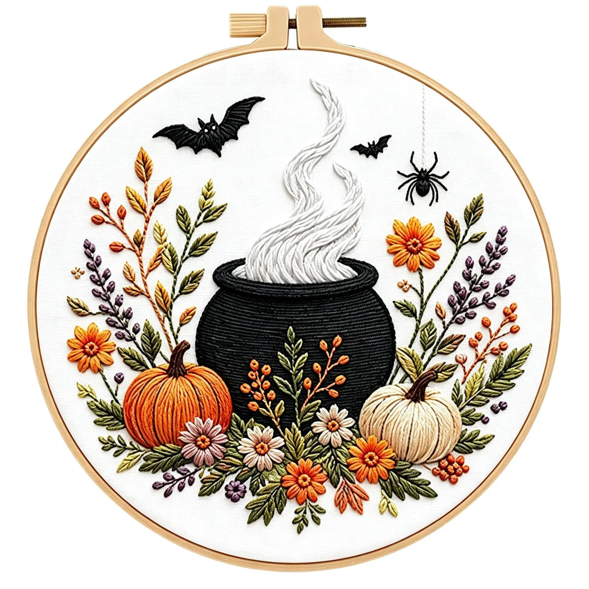 A circular embroidery design in a wooden hoop, featuring a black cauldron with white steam, orange and cream pumpkins, flowers, leaves, bats, and a spider on a white background.