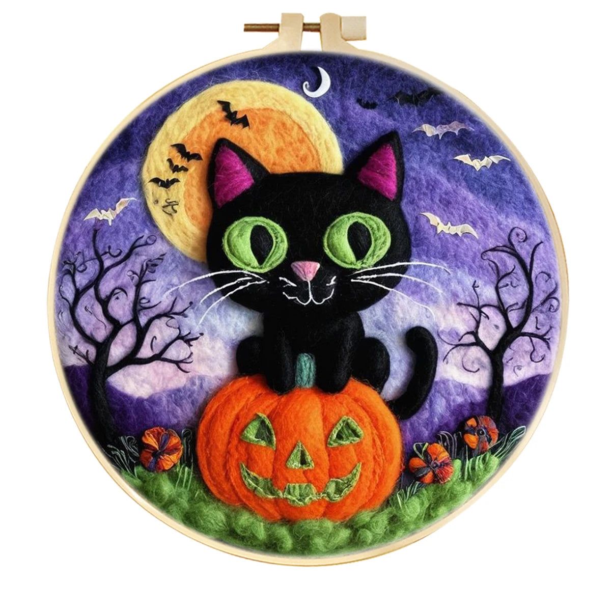 A circular needle felting piece featuring a black cat sitting on an orange jack-o'-lantern pumpkin, set against a purple night sky with a yellow moon, bats, silhouetted trees, and small flowers. The piece is displayed in a wooden hoop 