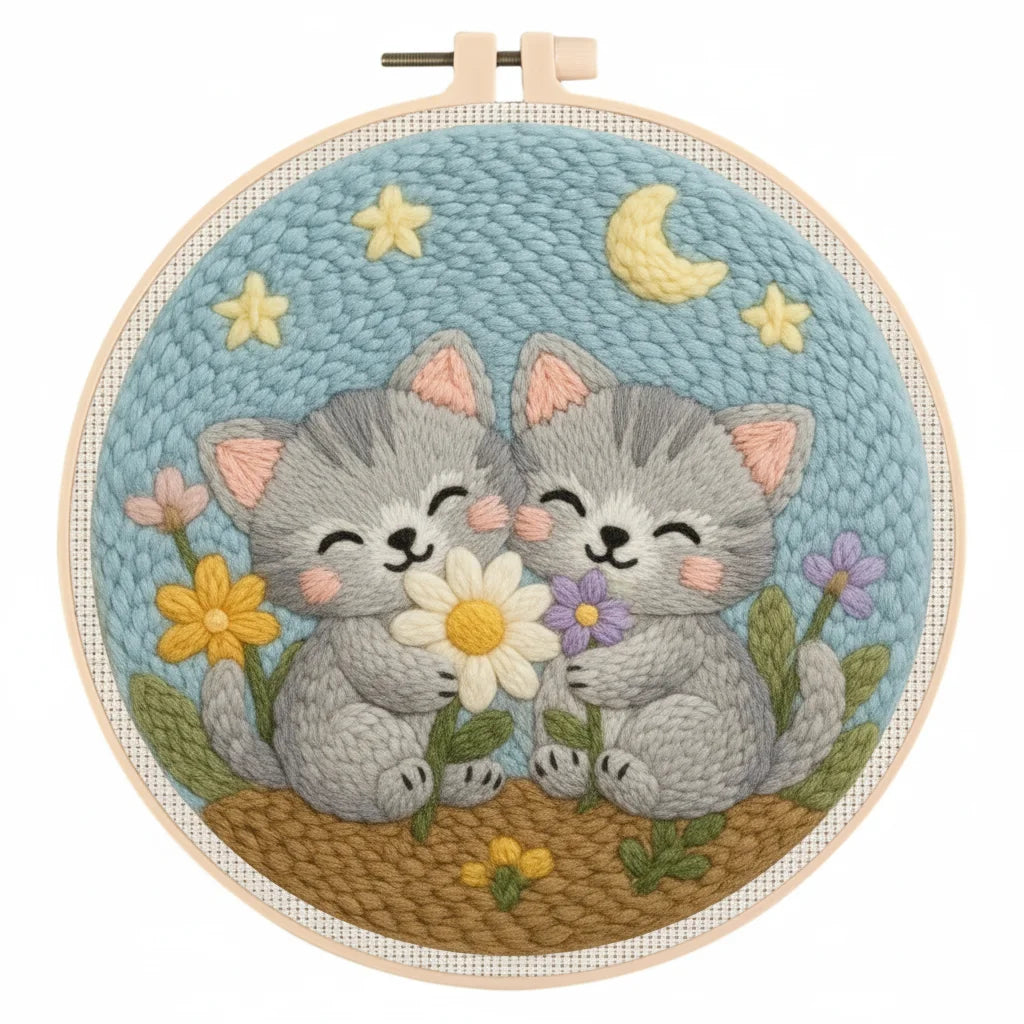 Embroidery hoop with two cartoon-style kittens holding flowers against a starry night sky.
