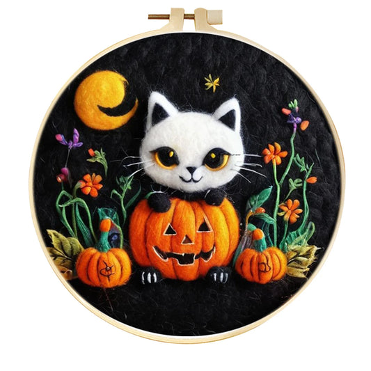 Embroidery hoop with a Halloween-themed needle felting design featuring a cat, pumpkins, and flowers.