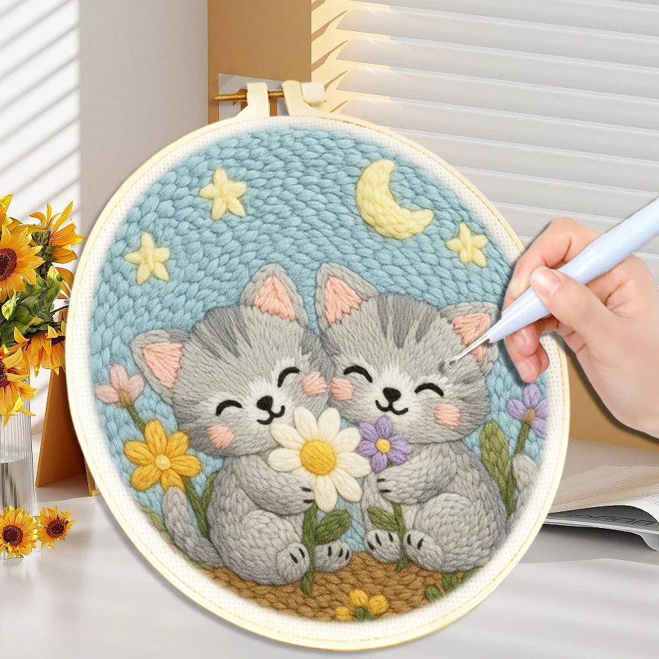 Embroidery hoop with two kittens surrounded by flowers and a moon and stars in the background.