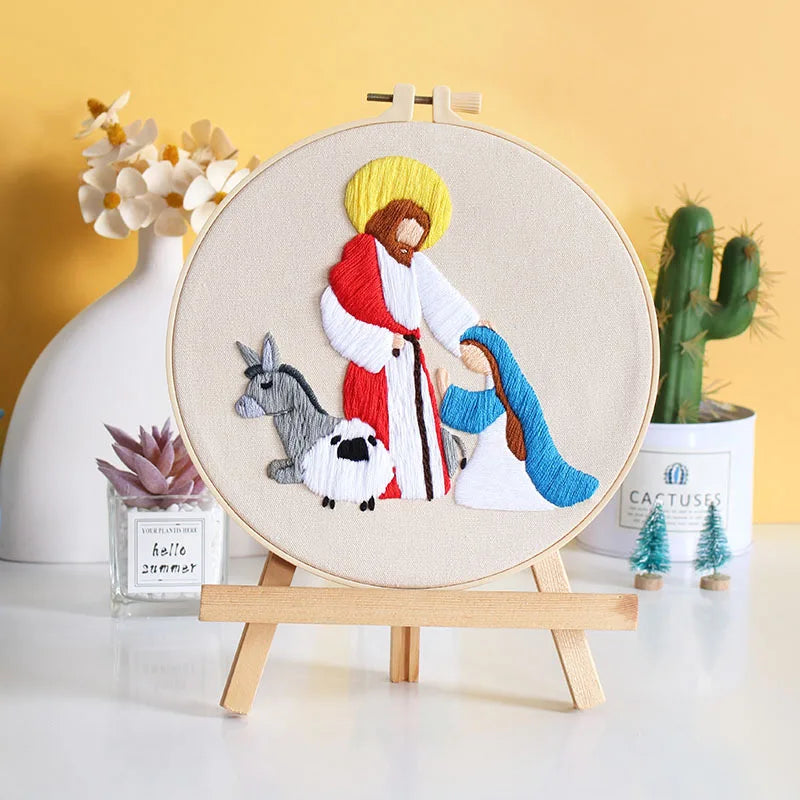 Embroidery in a hoop of a religious scene with a man, woman, donkey, and sheep on a wooden stand 