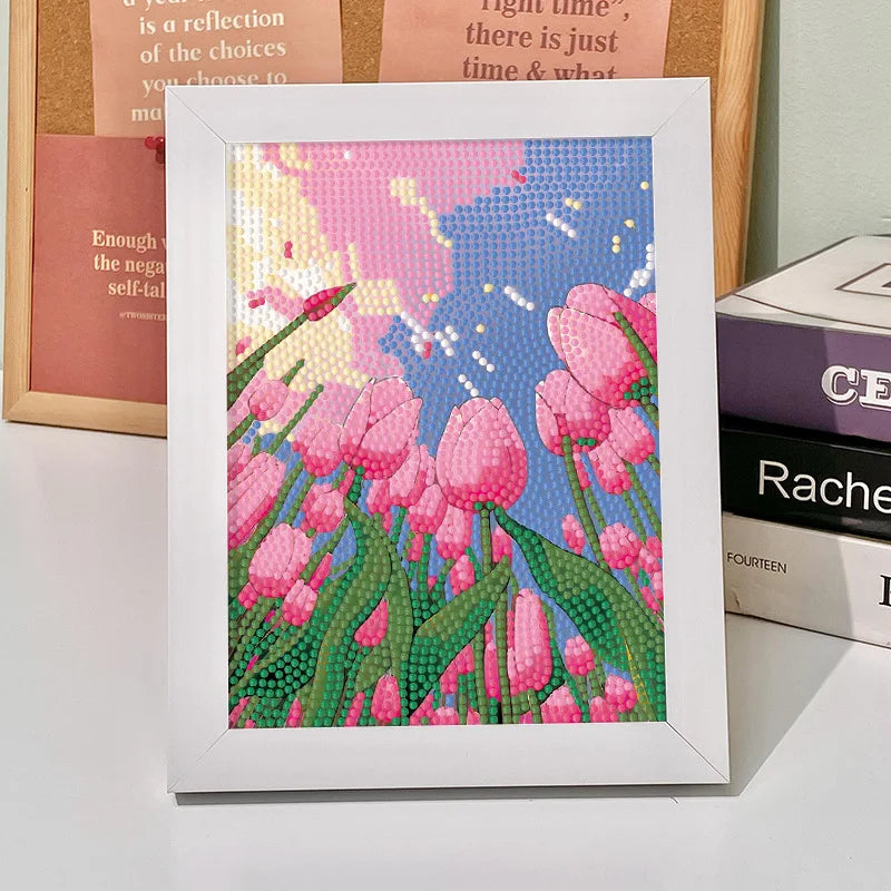 A framed diamond painting depicting pink tulips in a field under a blue and pink sky