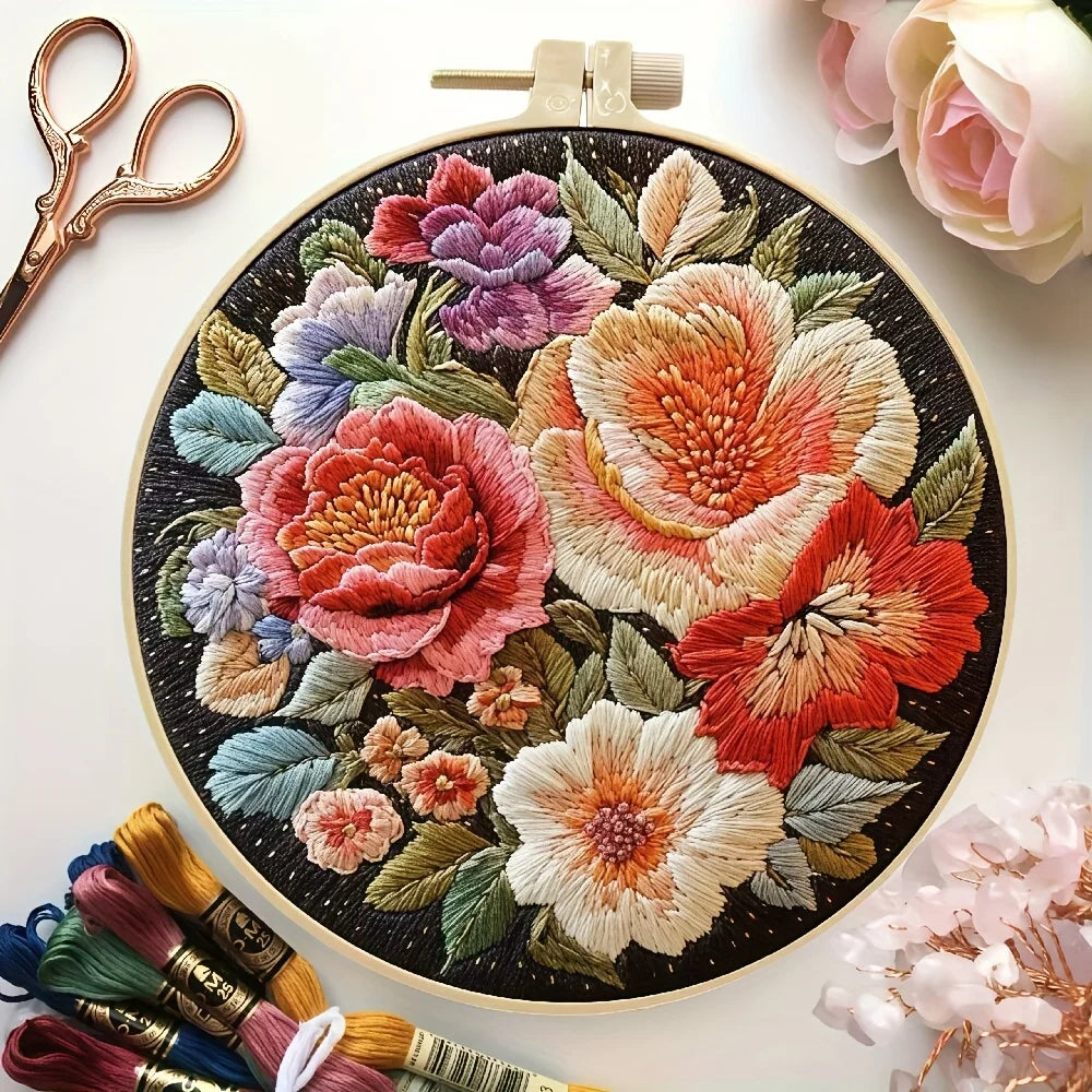Embroidery hoop with colorful floral embroidery on a white background with embroidery threads and scissors.
