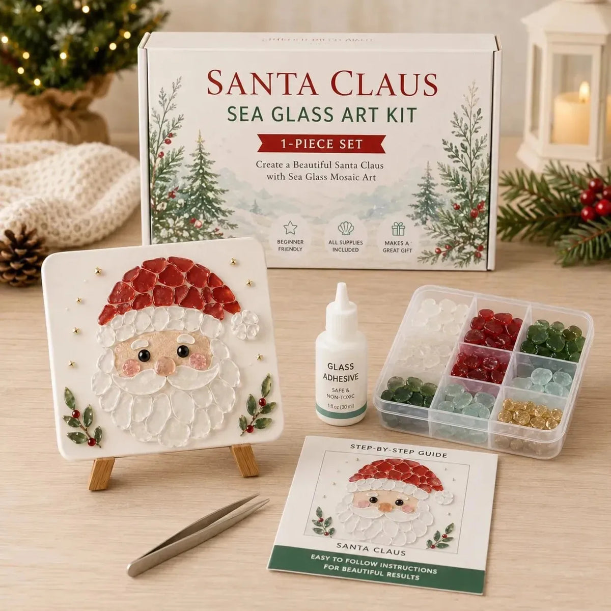 A Santa Claus sea glass art kit displayed on a wooden tabletop with its box, finished artwork tile, adhesive bottle, tray of colorful sea glass beads, instruction sheet, tweezers, and holiday decor in the background.