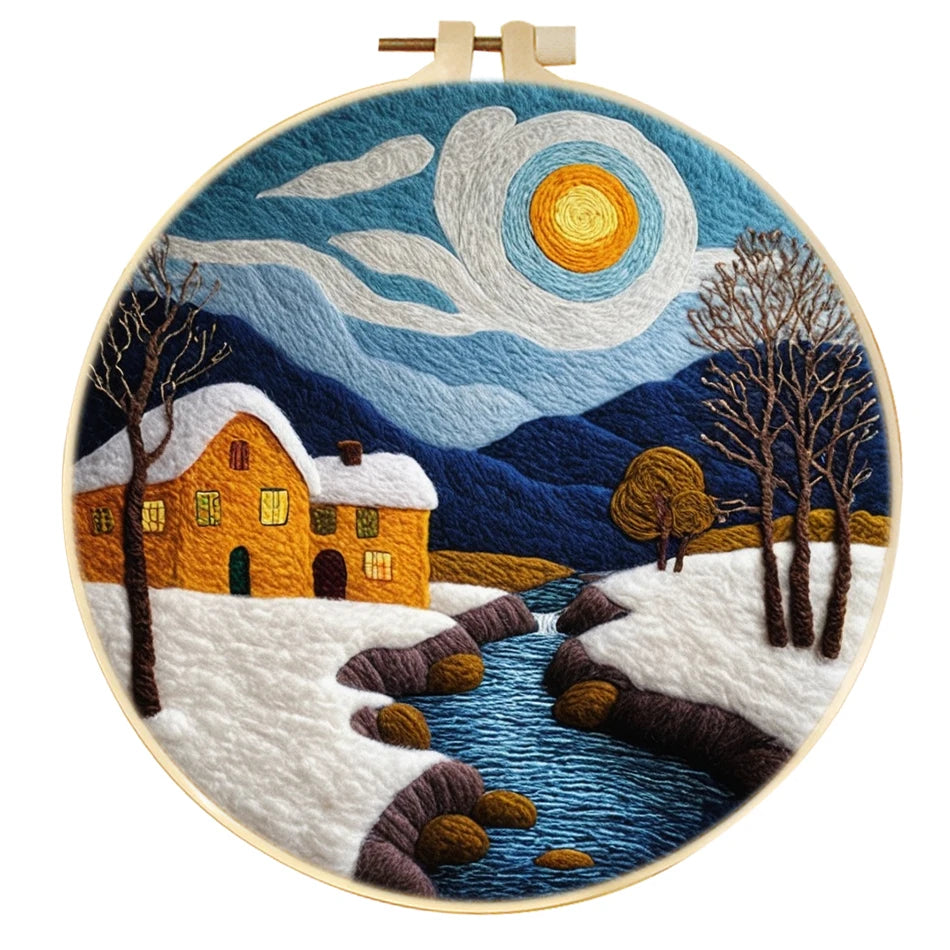 Needle felted winter scene, with blue sky, mountains, a stream, trees, and a house with snow on the roof.