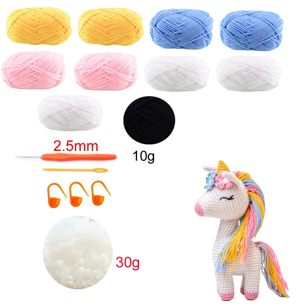 Crochet yarn balls in various colors, a crochet hook, and a crocheted unicorn toy with a yellow, blue and pink mane, and other supplies