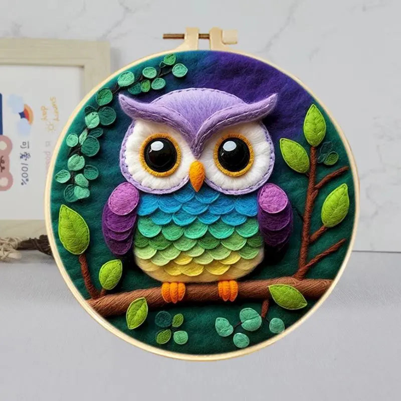 Colorful needle felted owl in a hoop frame in purple, yellow, orange, green and blue on a dark background