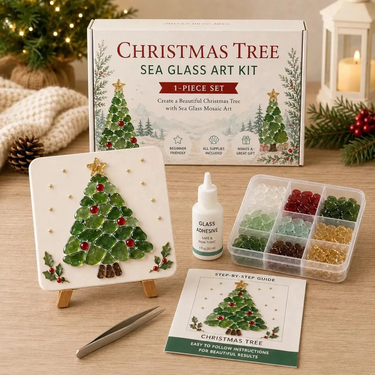 Christmas Tree Sea Glass Art Kit 1-piece set displayed on a wooden table with its box, finished artwork, glass shards in a tray, tweezers, and an instruction booklet. 