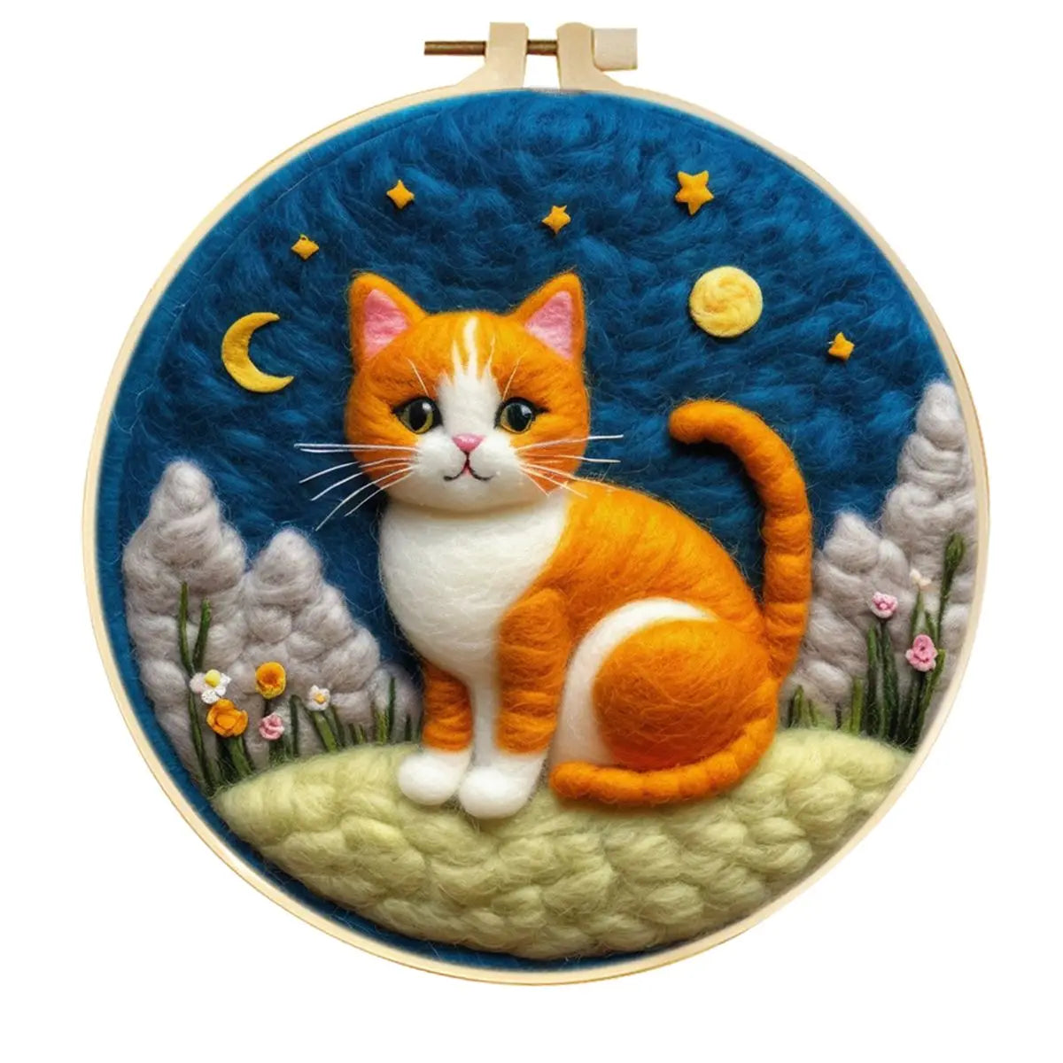 A circular hoop featuring a needle felted wool design of an orange and white cat sitting on a grassy hill under a dark blue night sky with stars, a crescent moon, and a yellow sun and some trees.