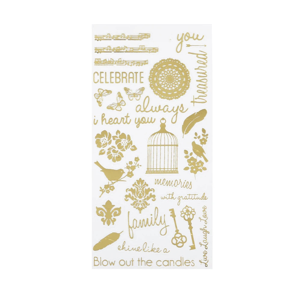 A sheet of clear stickers featuring elegant gold foil-style designs and phrases, including 'CELEBRATE', 'i heart you', 'family', 'memories with gratitude', and 'Blow out the candles'.