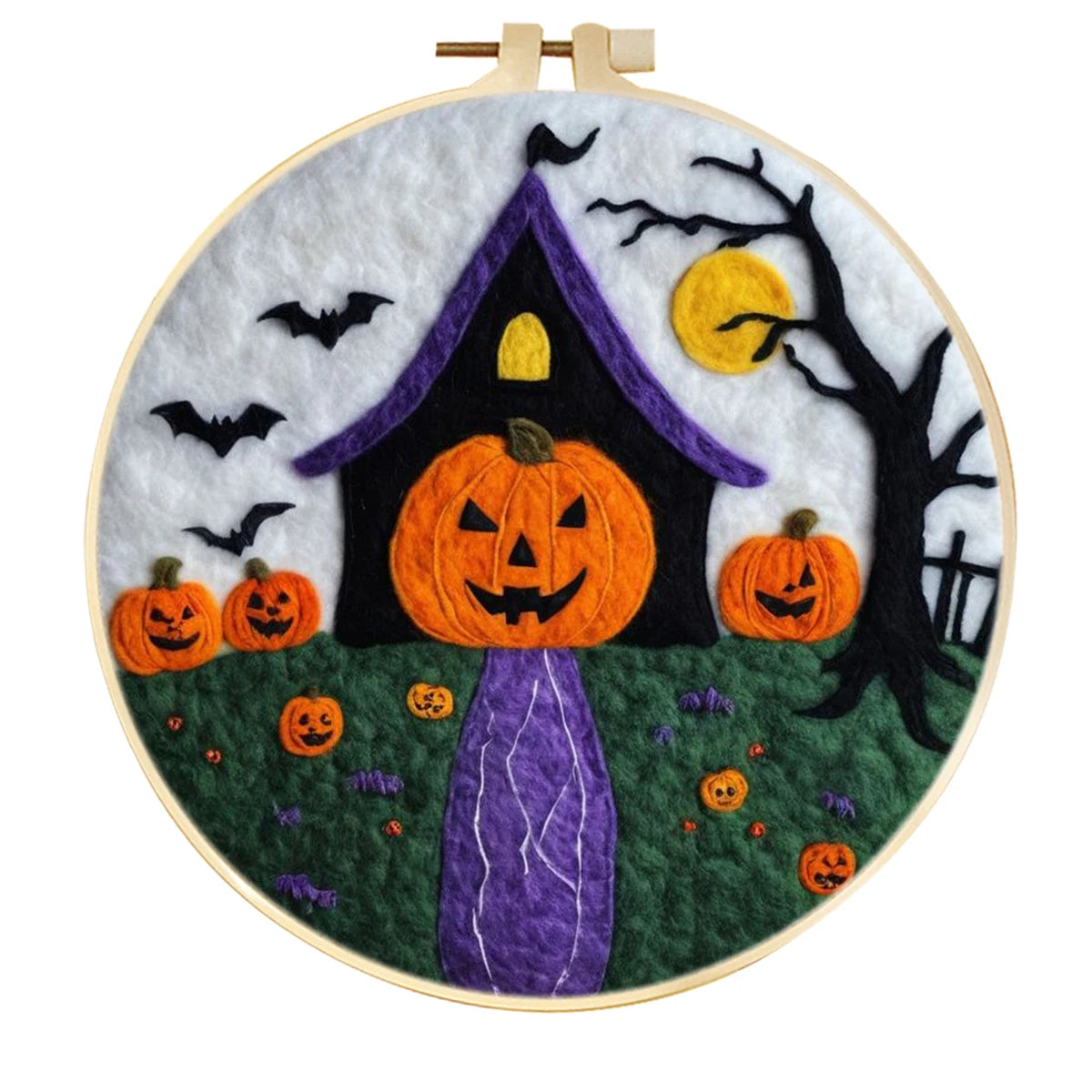 A circular embroidery hoop containing a Halloween-themedneedle felted design with a large orange jack-o'-lantern, smaller pumpkins, a purple haunted house, black bats, a black tree, green ground, and a yellow moon 