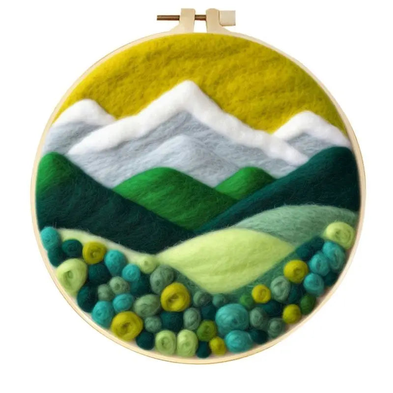 Embroidery hoop with a mountain landscape design using green, blue, and white colors.