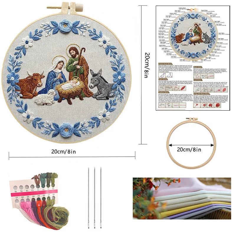 Embroidered kit shown in a circular wooden hoop with a nativity scene design, alongside a printed pattern sheet, hoop, embroidery floss, needles, and folded fabric 