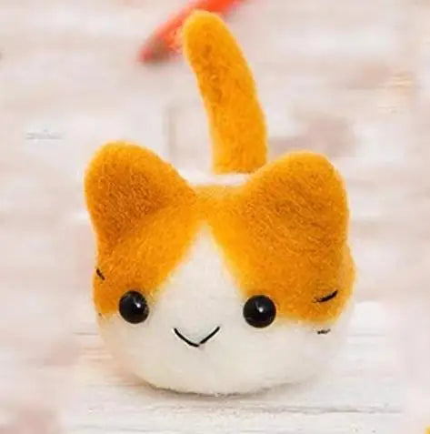 Felted cat that is white and orange with black eyes on a white background