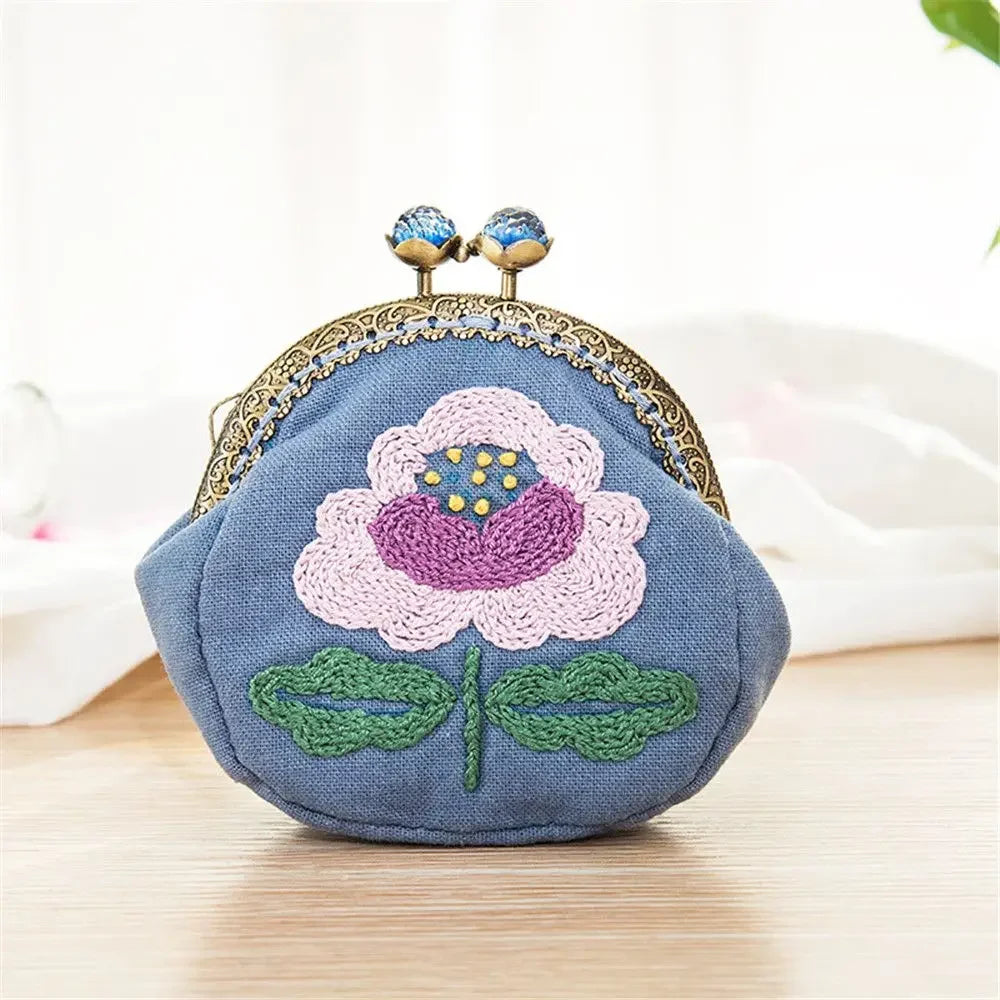 Small blue pouch with floral embroidery on a light wooden surface