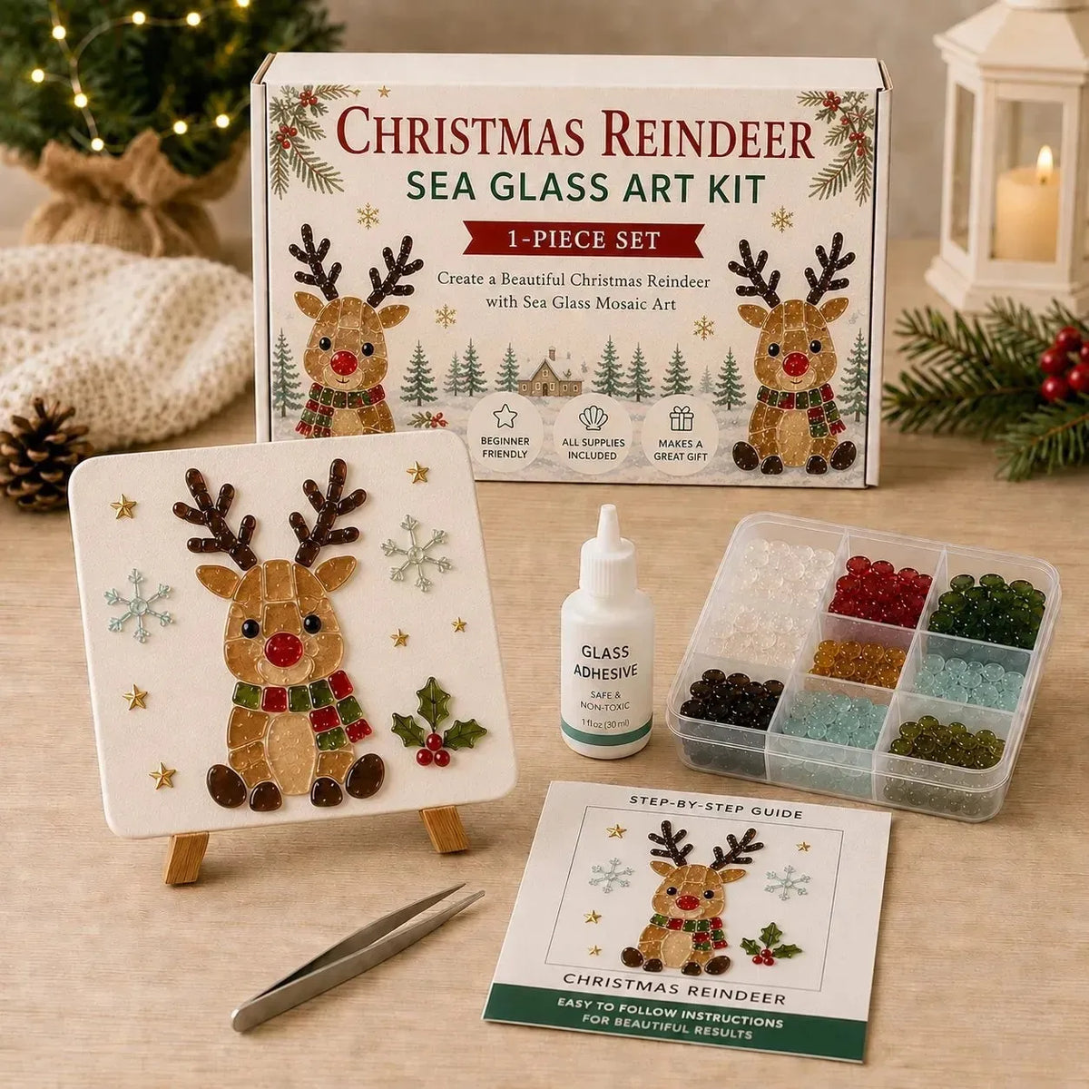 Christmas Reindeer Sea Glass Art Kit shown with its box, finished artwork on a small easel, adhesive bottle, glass bead tray, tweezers, and instruction sheet on a wooden surface with holiday decor in the background.