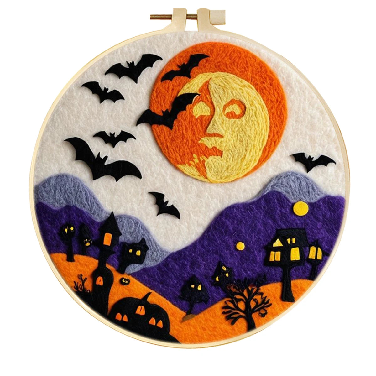 A circular embroidery hoop featuring a Halloween-themed needle felted artwork with a large orange and yellow moon, black bats, purple hills, orange ground, and spooky house and tree silhouettes 