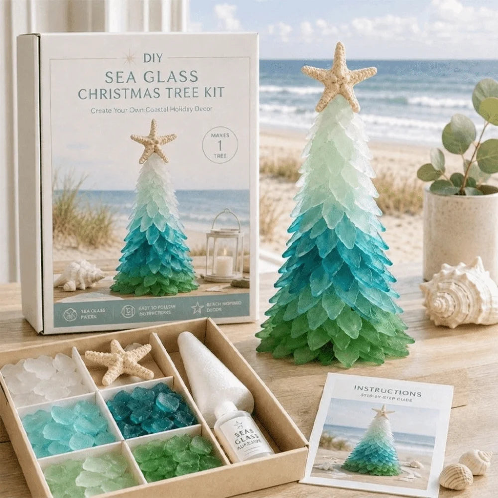 DIY Sea Glass Christmas Tree Kit displayed on a beach-themed surface with its packaging box, assembled tree, starfish topper, bottle, glass compartments, and instructions card. 