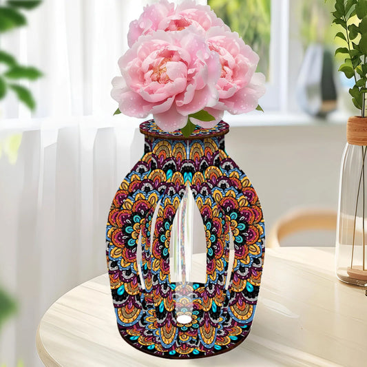 A decorative diamond art vase with a colorful mandala pattern and a clear glass center, filled with pink peony flowers