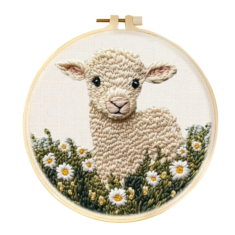 Embroidery hoop with a embroidered design of a lamb in a field on a white background
